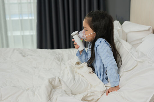 sick preschool child girl using respiratory nebulizer mask in bed