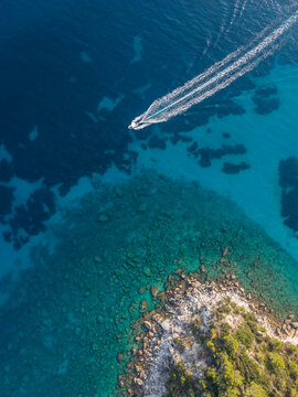 Aerial view of speedboat leaving wake near rocky coastline, Lakka, Paxos, Ionian Islands, Greece
