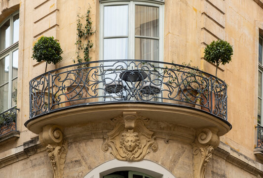 Detail of ornate wrought iron balcony with carved stone facade on a Haussmann-style building, Paris, France