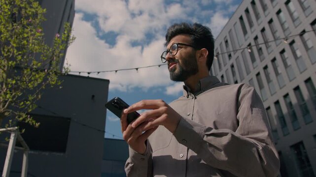 Confused Arabian Indian businessman lost using GPS smartphone outdoors in city male looking around street location tourist navigating map app geolocation guy exploring alone searching direction center