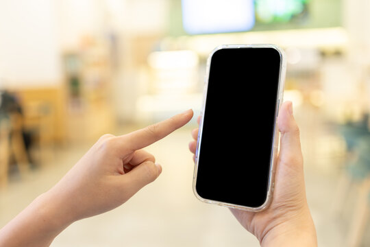 Closeup Hand Holding Smartphone Blank Screen Mockup Finger Pointing at Screen Blur Shop Background