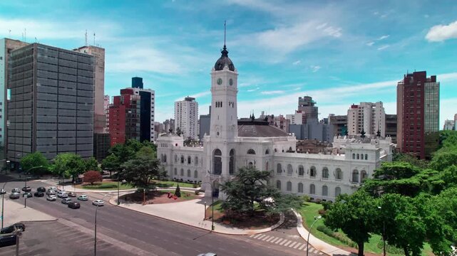 Aerial drone orbit shot panning smoothly in a curve around the front facade and clock tower of the German Neo-Renaissance City Hall in La Plata, Buenos Aires province, Argentina