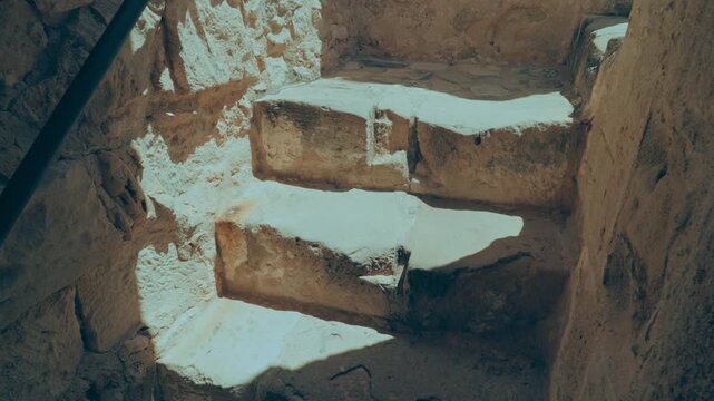 Ancient stone steps bathed in bright sunlight, leading deep into archaeological excavations in Limassol. 