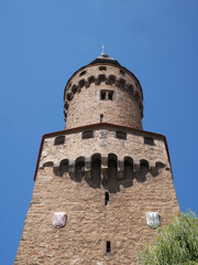 Dramatic low-angle view of the historic Reichenbacher Tower in Goerlitz with massive stonework, defensive corbels, coats of arms and round upper tower against a deep blue summer sky. © Frank
