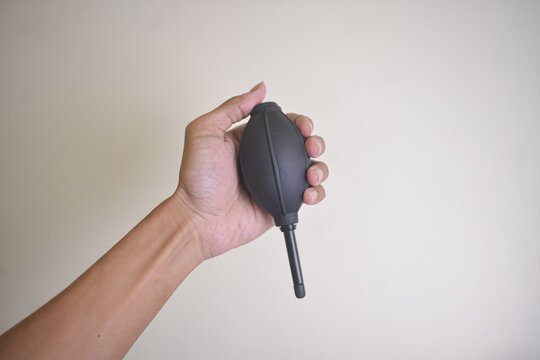 Hand Holding Black Camera Lens Rubber Air Blower Tool Against White Background