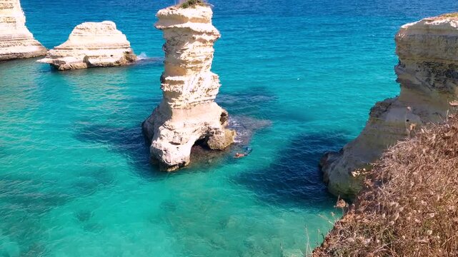 Faraglioni di Sant Andrea Otranto Puglia Italy swimmer snorkeling turquoise sea rock stacks coastal landscape scale secluded summer paradise travel destination 4k video, tropical sea in Europe