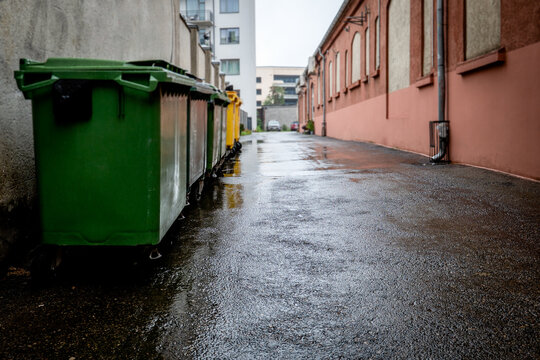 Colorful Waste Bins Along a Rainy Urban Alley