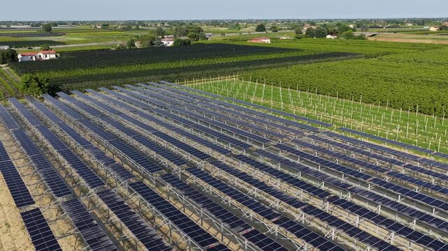 Aerial view of solar panels installed in a rural field surrounded by agricultural land and orchards in Faenza, Emilia-Romagna, Italy.