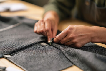 Fototapeta premium Hands expertly secure fabric fasteners, demonstrating the intricate work involved in garment creation, capturing the essence of craftsmanship and attention to detail.
