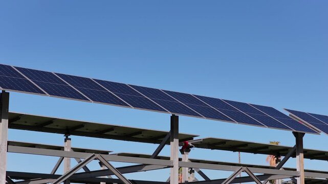 Aerial view of solar panels mounted on metal frames against a clear blue sky in Terrasini, Sicily, Italy.