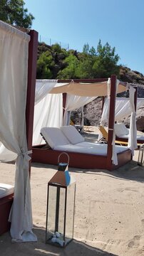 Elegant beach beds overlooking the turquoise sea, luxurious relaxation on a sandy beach surrounded by canopies and the Greek sun on the charming coast of Thassos, Greece