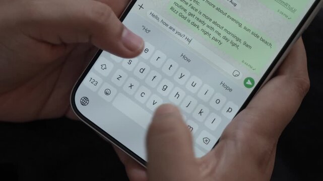 Woman's hand chatting and typing on a smartphone, macro closeup. Unrecognisable human typing a text message, tapping the touchscreen keyboard using the WhatsApp application, a social media.