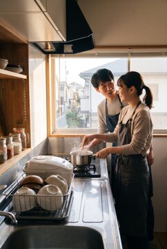Japanese pair cooking together beside the kitchen stove