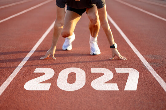 Sprinter crouching in starting position on running track with 2027 text, athlete ready to race new year concept