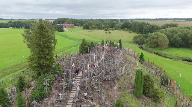 Aerial view of the Hill of Crosses featuring thousands of crosses on a hill surrounded by green fields in Jurgaiciai, Siauliu apskritis, Lithuania.