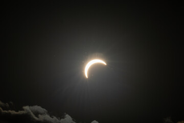 Partial solar eclipse captured as the Moon passes in front of the Sun, creating a striking crescent shape against the dark sky. An astronomical event photographed during daylight. © KjLOWRYPHOTOGRAPHY