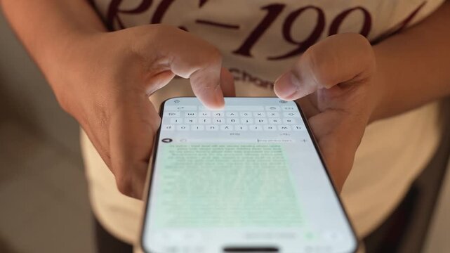 Woman's hand chatting and typing on a smartphone, macro closeup. Unrecognisable human typing a text message, tapping the touchscreen keyboard using the WhatsApp application, a social media.