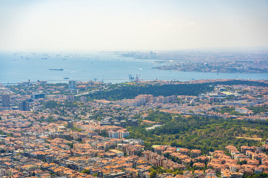 Aerial view of Istanbul cityscape featuring residential buildings, green parks, and the Bosphorus Strait with ships in the distance in Istanbul, Turkey 