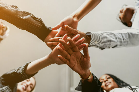Diverse group of people joining hands in a circle, symbolizing teamwork and unity.