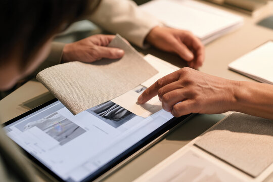 Two individuals engage digitally, exploring fabric samples on a tablet, emphasizing modern technology's role in selecting materials for fashion design.