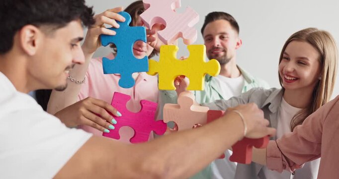 Students teamwork collaboration puzzle cooperation group activity. Young people connect colorful jigsaw pieces, symbolizing education, project planning and unity. Clear concept of teamwork and unity.