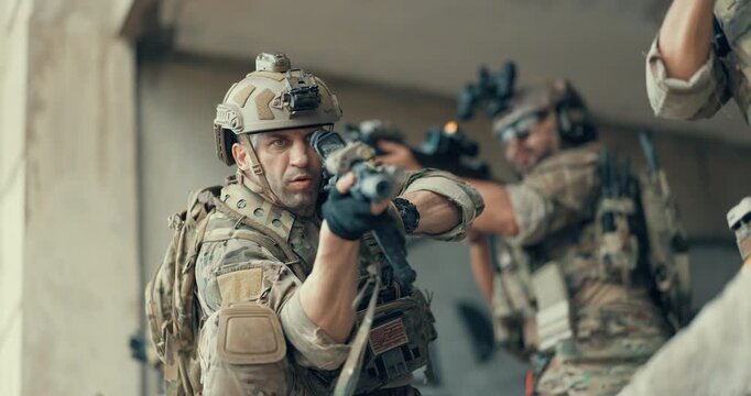 Close up of military tactical operator aiming suppressed rifle in abandoned building