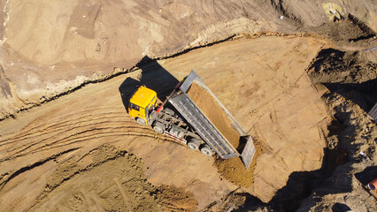 Aerial View of Yellow Dump Truck Unloading Sand at Construction Site © Andrey