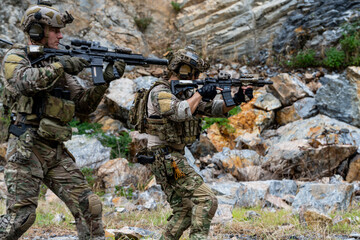Fototapeta premium Soldiers practice tactics in rocky terrain during day training session with rifles