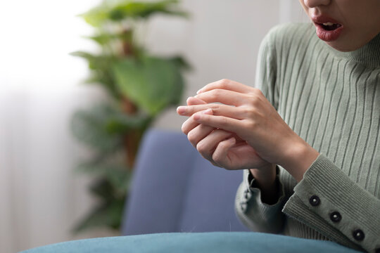 A young woman is experiencing pain in her hands and fingers and is trying to relieve the discomfort by massaging them gently.