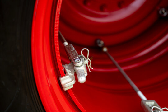 Metal dual wheel clamp latch mechanism with cotter pin installed on red rim flange of heavy agricultural machinery.