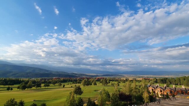 Scenic Golf Course Landscape with Rolling Greens, Trees and Distant Mountains Under Dramatic Clouds