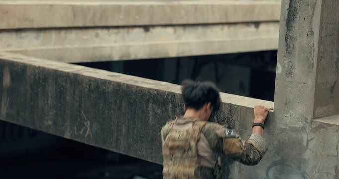 Military tactical operator climbs over concrete beam and takes cover in ruined building