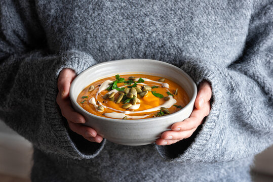 Bowl of pumpkin soup in woman hands