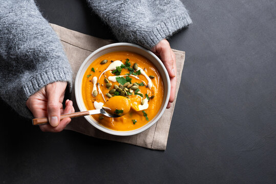 Woman in knitted sweater eating fresh pumpkin soup