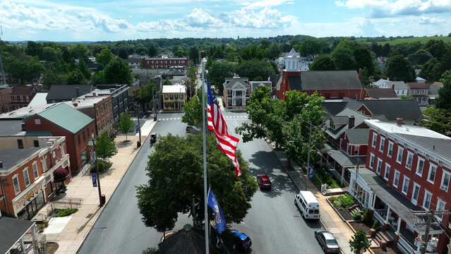 Aerial view of the historic town center featuring a prominent American flag, brick buildings, and tree-lined streets in Manheim, Pennsylvania, United States.