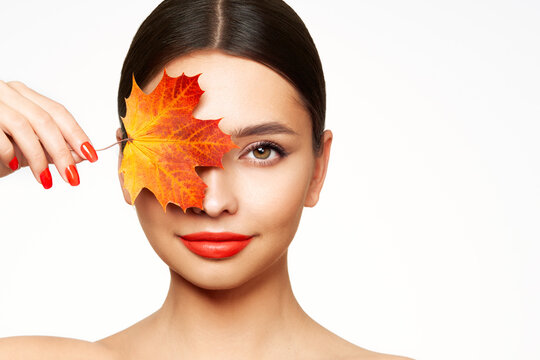 Portrait of beautiful young woman with autumn leafs. Healthy clean fresh skin natural make up beauty eyes and red nails