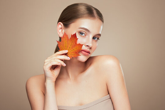 Portrait of beautiful young woman with autumn leaves. Healthy clean fresh skin natural make up beauty eyes