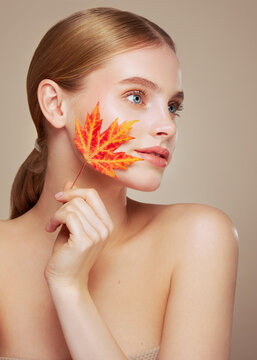 Portrait of beautiful young woman with autumn leaves. Healthy clean fresh skin natural make up beauty eyes