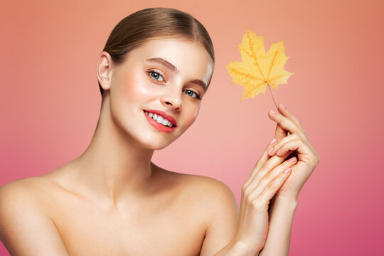 Portrait of beautiful young woman with autumn leaves. Healthy clean fresh skin natural make up beauty eyes