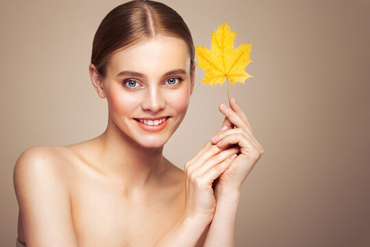Portrait of beautiful young woman with autumn leaves. Healthy clean fresh skin natural make up beauty eyes