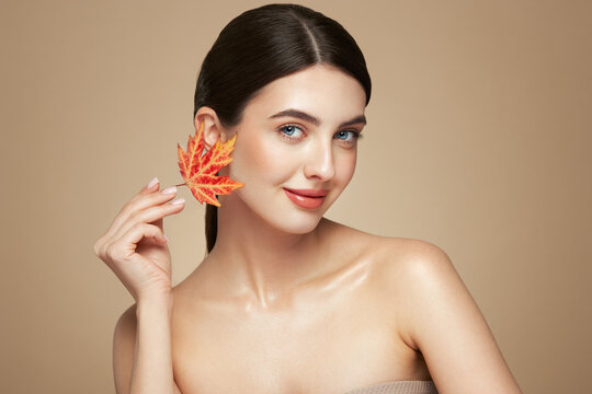 Portrait of beautiful young woman with autumn leafs. Healthy clean fresh skin natural make up beauty eyes