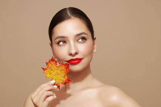 Portrait of beautiful young woman with autumn leafs. Healthy clean fresh skin natural make up beauty eyes