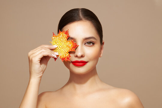 Portrait of beautiful young woman with autumn leafs. Healthy clean fresh skin natural make up beauty eyes