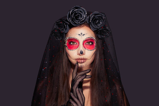 Portrait of a woman with sugar skull makeup over black background. Halloween costume and make-up. Portrait of Calavera Catrina