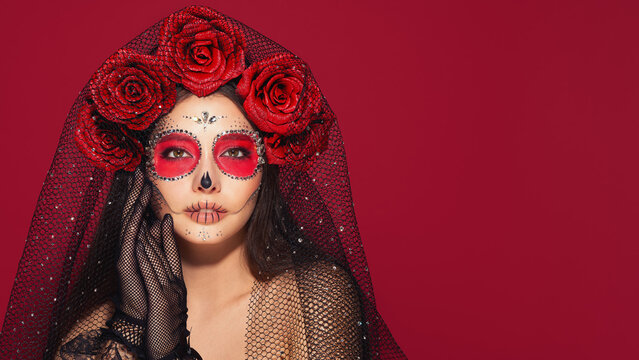Portrait of a woman with sugar skull makeup over red background. Halloween costume and make-up. Portrait of Calavera Catrina
