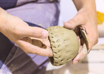 Hands decorating a rounded clay vessel © mitarart