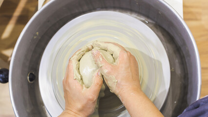 Hands shaping a clay vessel on a pottery wheel © mitarart