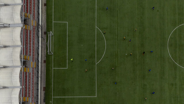 Aerial view of a soccer match in progress at a stadium with players on the green pitch and red seating in the stands in Lagos, Lagos, Nigeria.