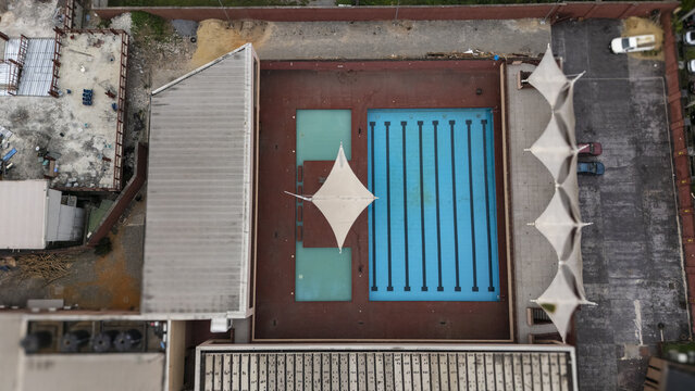 Aerial view of Lagos Island swimming pool complex featuring a large rectangular pool and a smaller pool with white shade sails on a red deck in Lagos, Lagos, Nigeria.