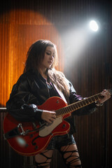 Fototapeta premium A beautiful teenage girl is happily playing the guitar.